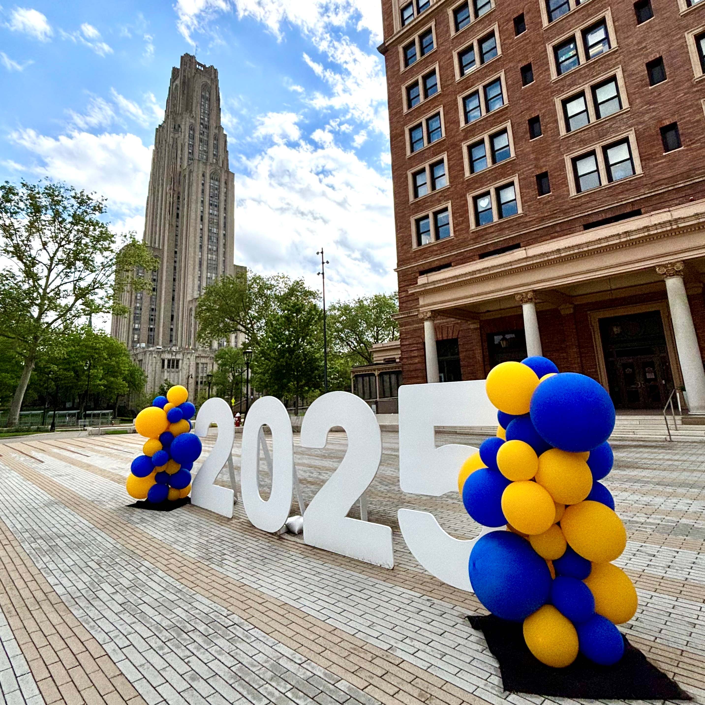 photo of large 2025 sign with cathedral of learning in the background