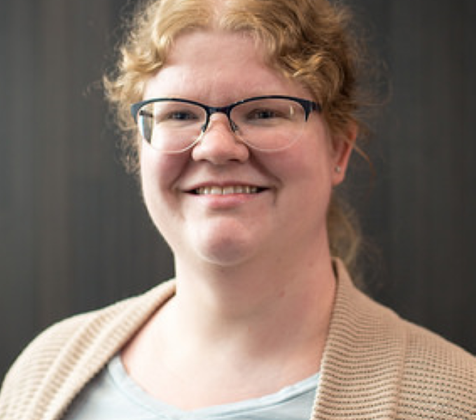 Christy headshot. beige sweater over gray top.
